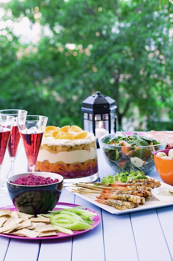 A Table In The Garden, Laid With Prawn Skewers, Beetroot Dip, Spinach Salad And A Trifle Photograph by Young, Andrew