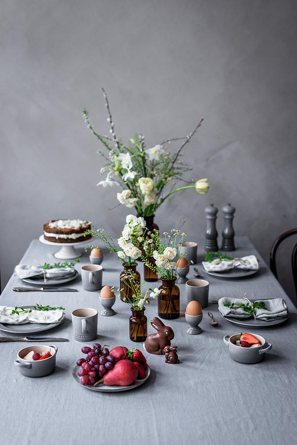 A Table Laid For An Easter Breakfast With Boiled Eggs, Carrot Cake, Chocolate Bunnies And Fruit Salad Photograph by Carolin Strothe