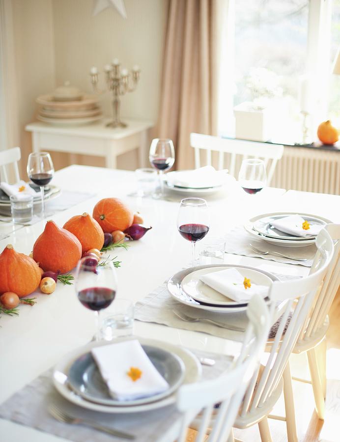 A Table Laid For Thanksgiving Decorated With Pumpkins And Onions With Glasses Of Red Wine At Each Place Photograph by Hannah Kompanik