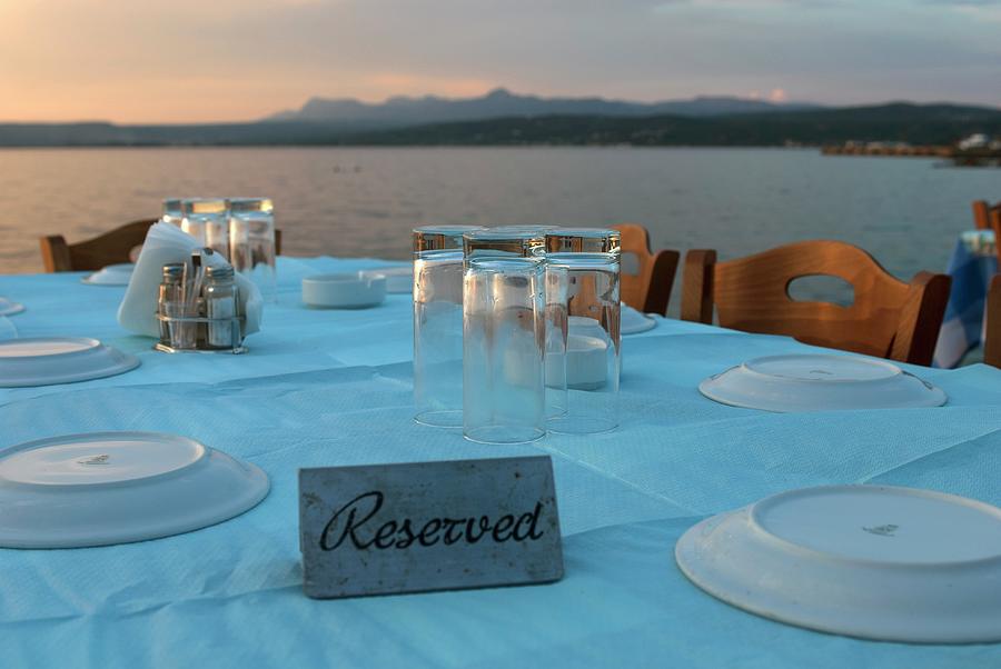 A Table Laid With A Pastel-blue Tablecloth With The Greek Coast In The Background Photograph by Spyros Bourboulis
