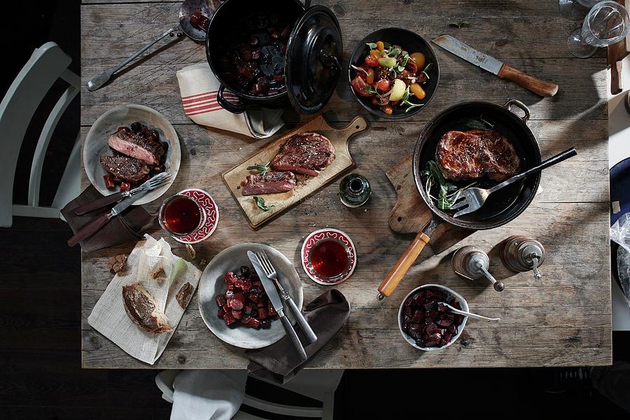A Table Laid With Tomato Salad, Steak And Stew Photograph by Rafael Pranschke