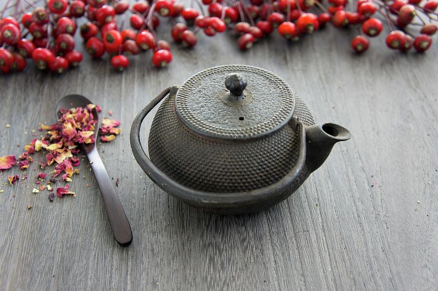 A Teapot, Rosehips And Dried Wild Rose Petals Photograph by Martina Schindler