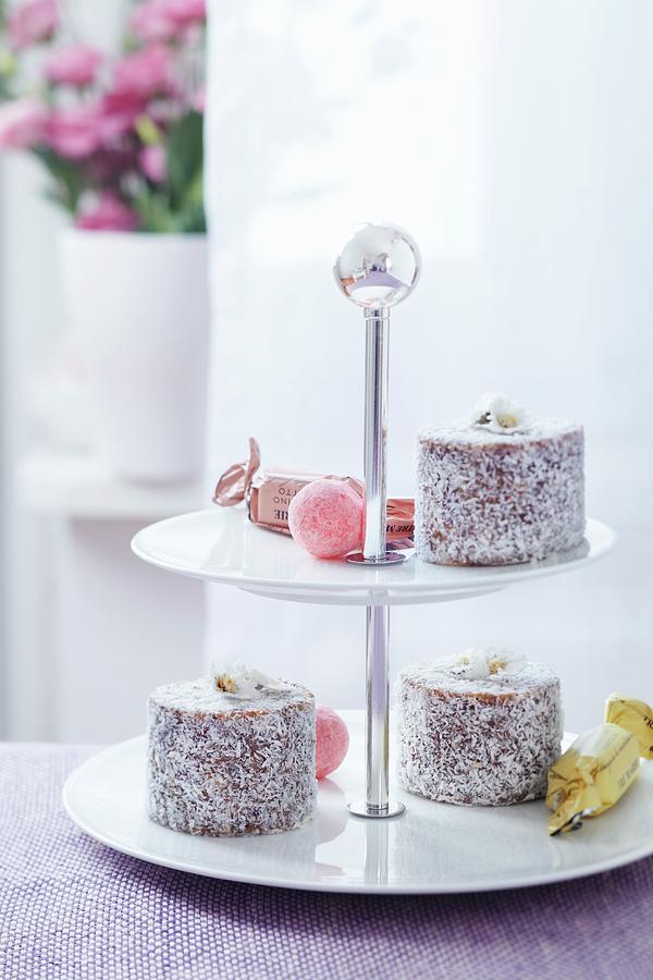 A Tiered Cake Stand With Filled Chocolates And Mini Coconut Tortes With Candied Daisies Photograph by Taube, Franziska