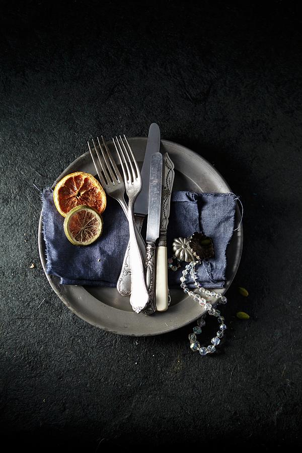 A Tin Plate With A Blue Cloth, Antique Cutlery, A Necklace And Dried Citrus Fruits Photograph by Kirchherr, Jo