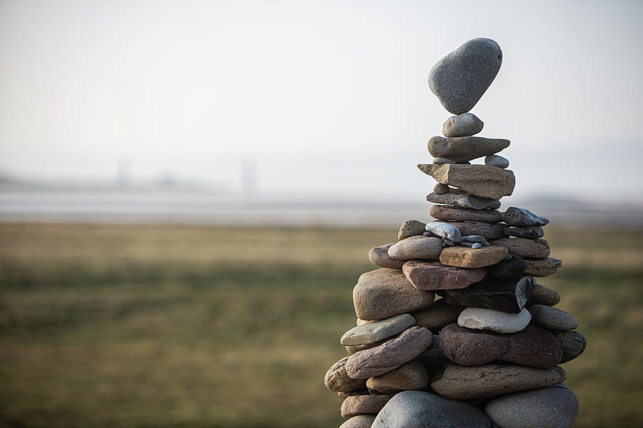 Nature Digital Art - A Tower Of Stones Of Various Sizes Stacked In A Cairn, The Top Stone Balancing On A Point. by Timm Cleasby Photography