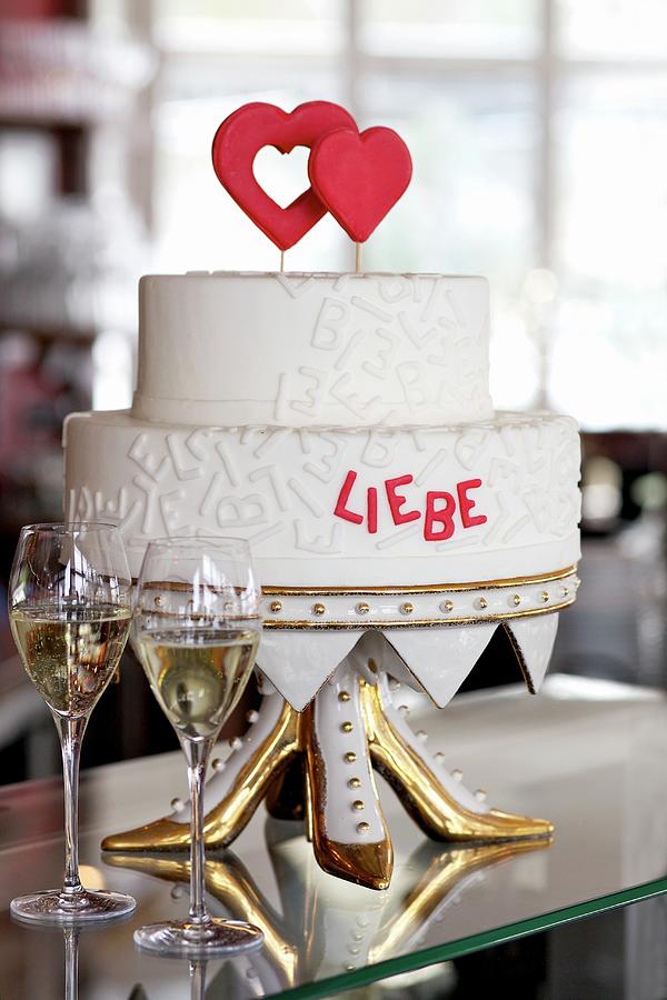 A Two-tier Wedding Cake With Red Hearts And Red Writing On An Unusual Cake Stand Photograph by Fotos Mit Geschmack