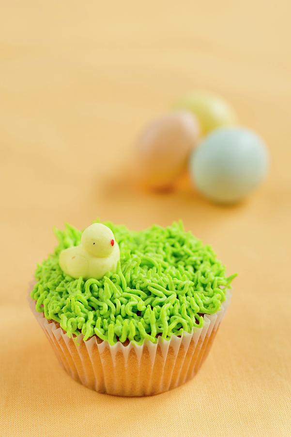 A Vanilla Cupcake Decorated With Grass And A Chick For Easter Photograph by Ewa Rejmer