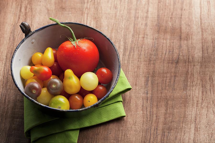 A Variety Of Tomatoes In An Antique Enamel Bowl On Wood Background With A Green Napkin Photograph by Albert P Macdonald