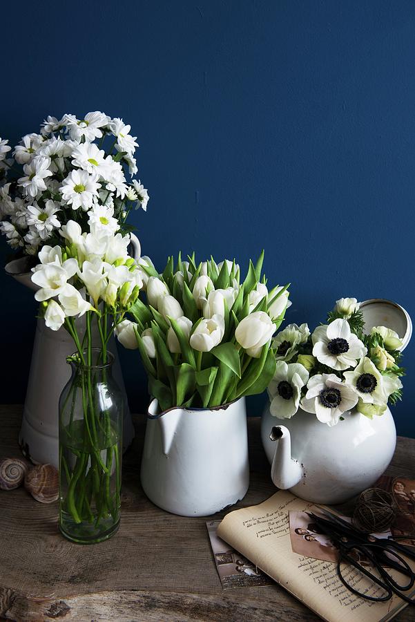 A Variety Of White Flowers In Full Bloom In Vintage Containers In Front Of A Blue Wall Photograph by Veronika Studer
