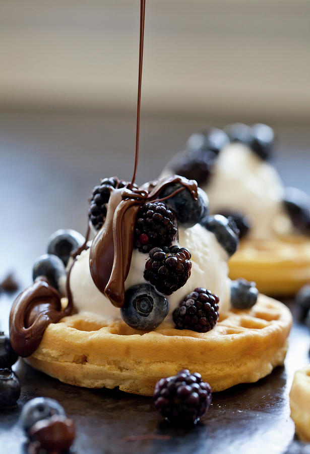 A Waffle Topped With Ice Cream And Frozen Berries Being Drizzled With Melted Chocolate Photograph by Ryla Campbell