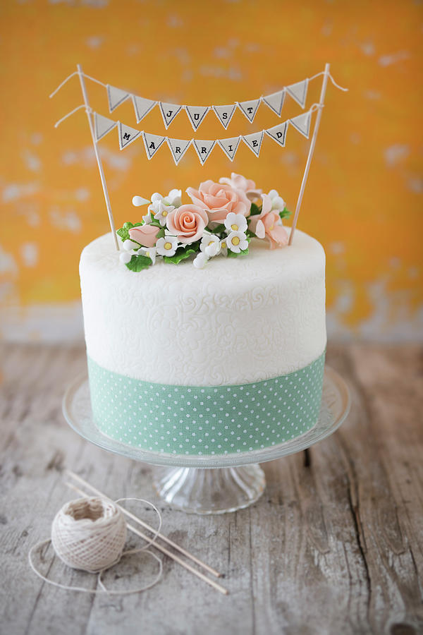 A Wedding Cake With Sugar Flowers, A Ribbon And A just Married Bunting Decoration Photograph by Jan Wischnewski