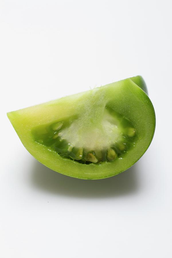 A Wedge Of Green Tomato On A White Surface Photograph by Eising Studio