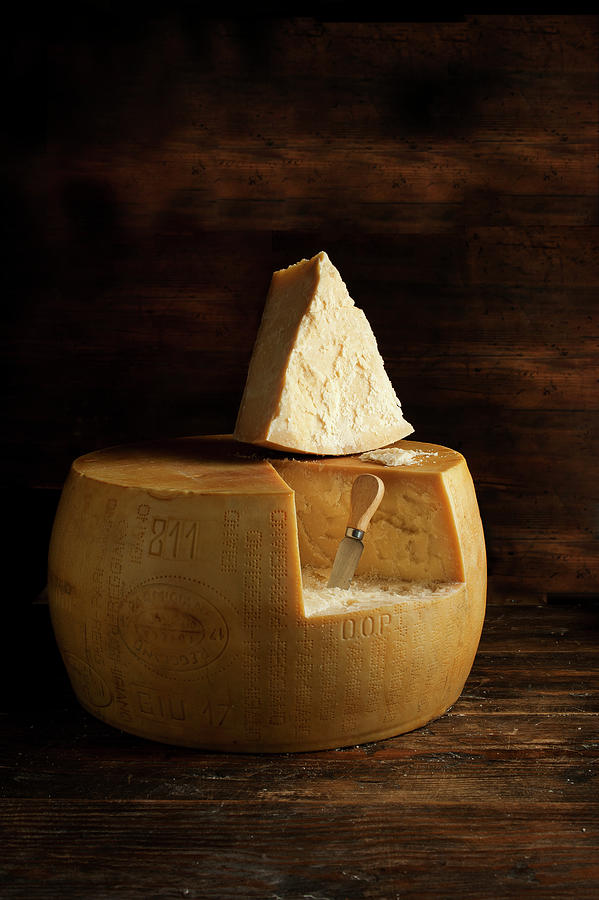 A Wheel Of Parmesan Cheese With A Slice Cut Out Photograph by William Reavell