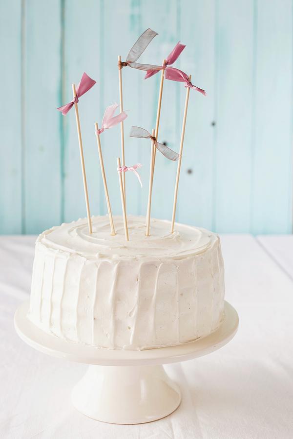 A White Birthday Cake With Pink Flags On A Cake Stand Photograph by Maricruz Avalos Flores