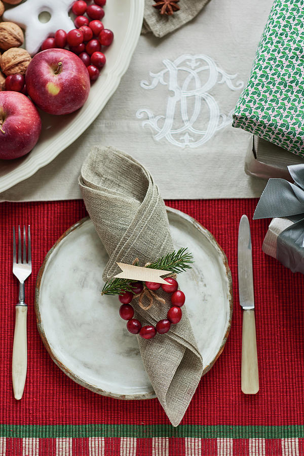 A White Ceramic Plate With A Fork And Knife Beside It On A Christmas Table With A Red Tablecloth Photograph by Edyta Girgiel