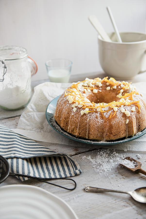 A White Chocolate Bundt Cake With Orange Zest On A Table With Baking Utensils Photograph by Magdalena Hendey