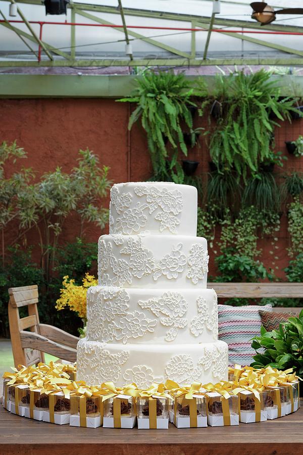 A White, Four Tier Wedding Cake With Mini Boxes Of Pralines As Gifts Photograph by Karl Stanzel