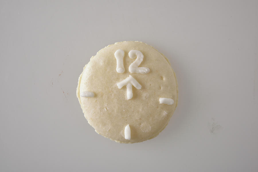 A White Macaroon Decorated To Look Like A Clock With An Arrow Pointing To The 12 Photograph by Great Stock!