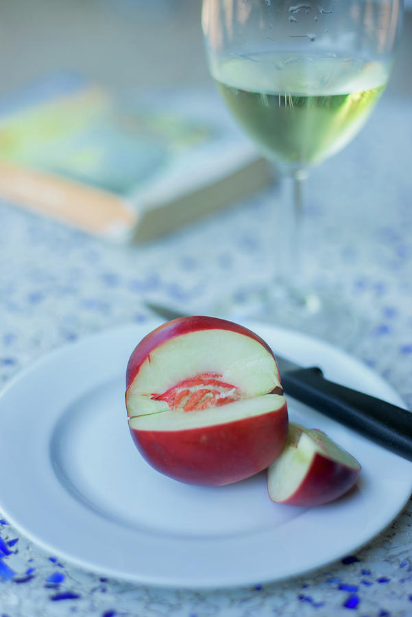 A White Nectarine, Sliced With A Knife On A Plate With A Glass Of White Wine Photograph by Roger Stowell