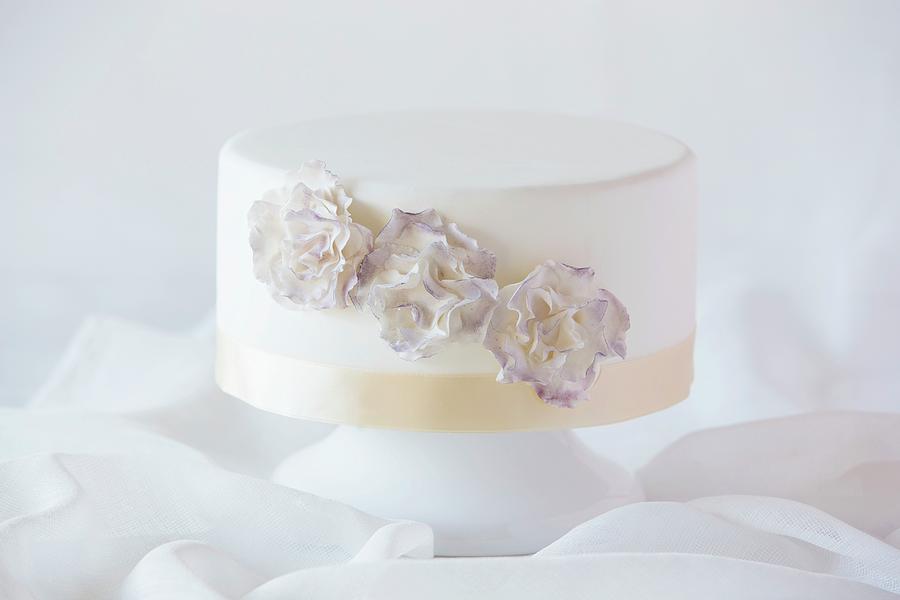 A White Wedding Cake Decorated With Flowers Photograph by Lydie Besancon