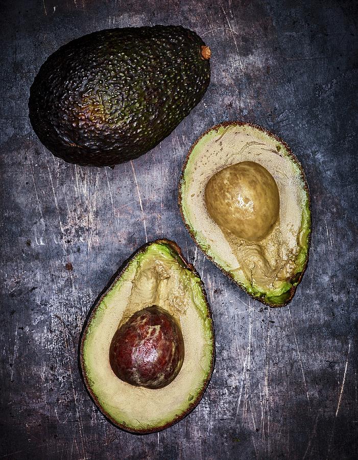 A Whole And A Halved Avocado On A Grey Surface seen From Above Photograph by Peter Rees