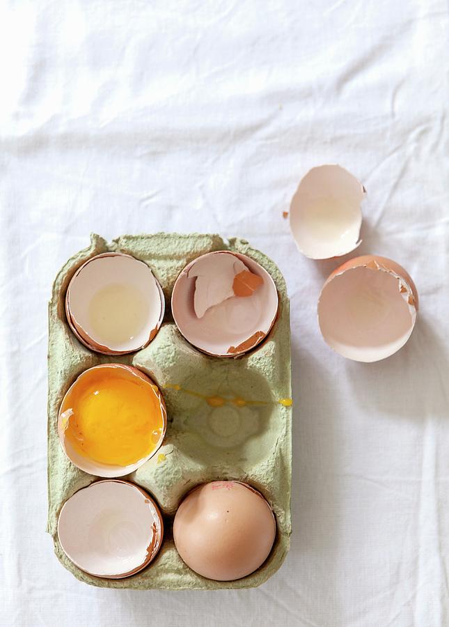 A Whole Egg, Empty Eggshells And A Cracked-open Egg In An Egg Box Photograph by Stacy Grant