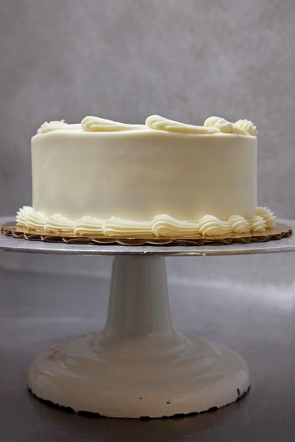 A Whole Layer Cake With Buttercream And Caramel Dots On A Cake Stand ...