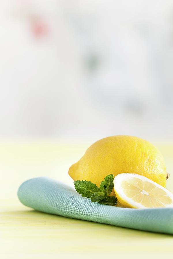 A Whole Lemon, A Slice Of Lemon, And Mint Leaves Photograph by Younes Stiller