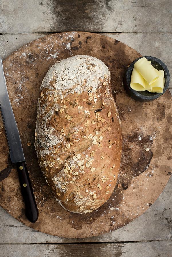 A Whole Loaf Of Wholemeal Bread On A Baking Stone With A Butter Dish Photograph by Magdalena Hendey