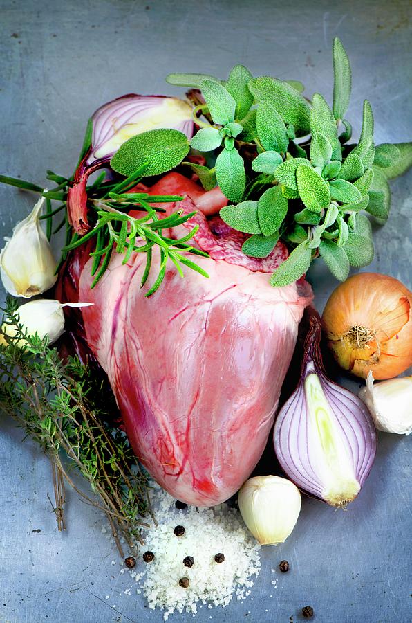 A Whole Pigs Heart Surrounded By Sage, Rosemary, Thyme, Onions, Garlic, Salt And Pepper Photograph by Jamie Watson