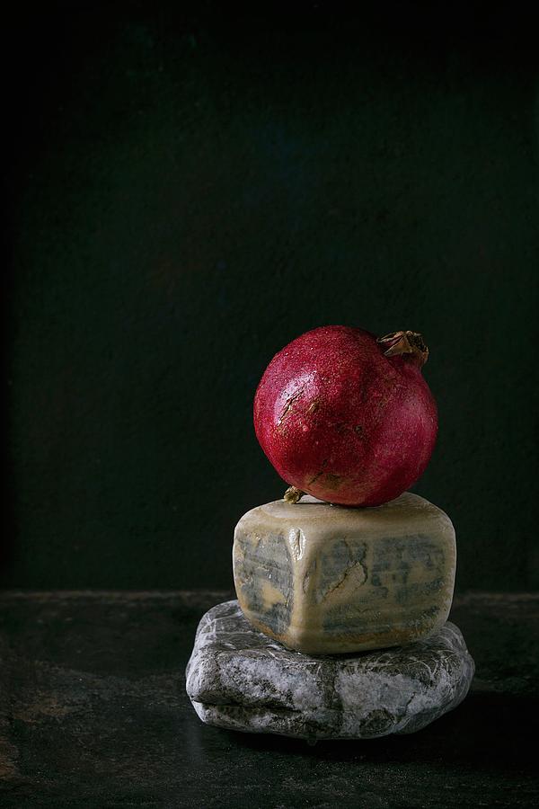 A Whole Pomegranate On Decorative Stones Against A Black Background Photograph by Natasha Breen