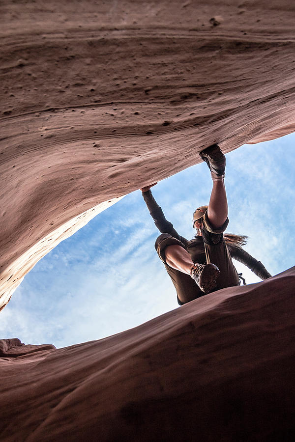 Architecture Photograph - A Woman Canyoneer Starts An Exposed Downclimb On Slick Sandstone Walls by Cavan Images