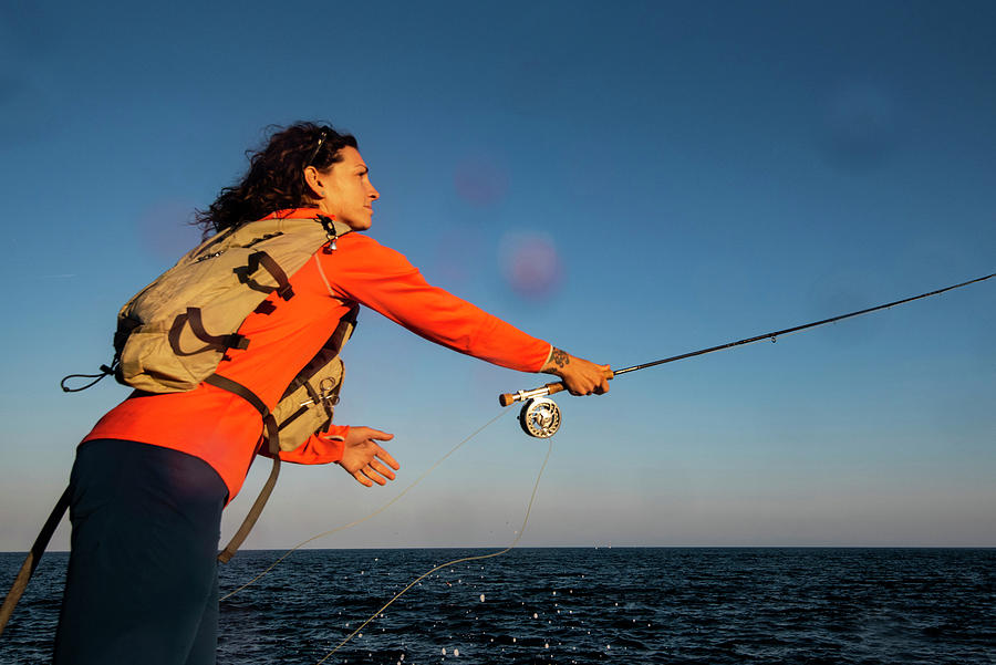 A Woman Casting A Fly Rod Along The Coast Of Maine by Cavan Images
