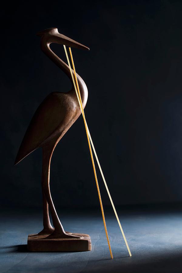 A Wooden Bird With Two Strands Of Dried Spaghetti Photograph by Mandy Reschke