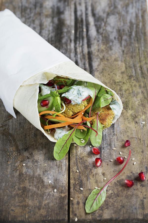 A Wrap With Falafel, Pomegranate Seeds, Mint, Cucumber, Beetroot Leaves And Dill Yoghurt Photograph by Tina Engel