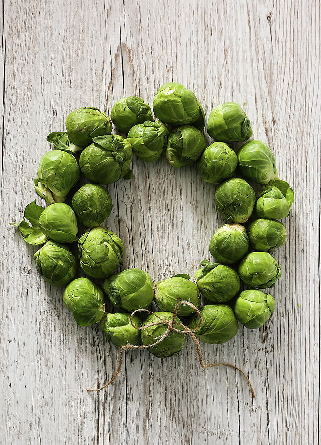 A Wreath Of Brussels Sprouts On A White Wooden Background Photograph by Stacy Grant