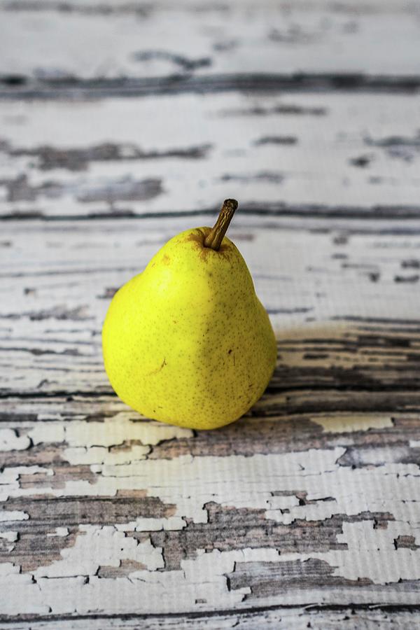 A Yellow Pear On A Rustic Wooden Table Photograph by Alena Haurylik