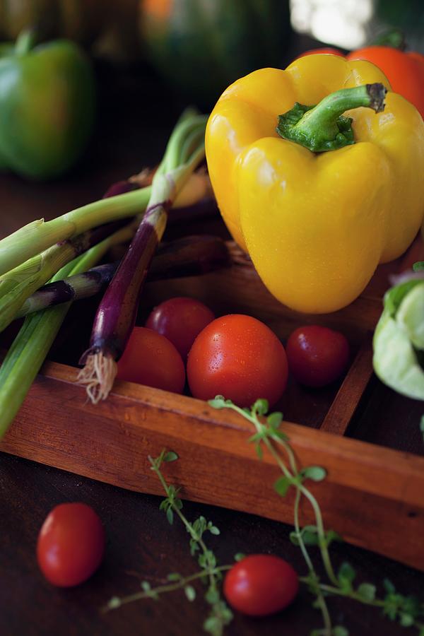 A Yellow Pepper, Red Spring Onions, Cherry Tomatoes And Herbs In A Wooden Crate Photograph by Katharine Pollak