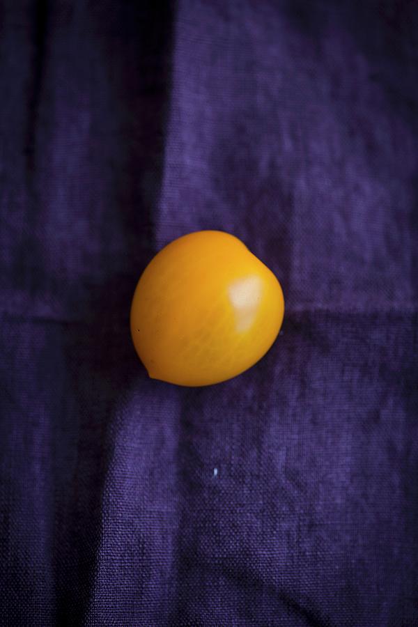 A Yellow Tomato On A Violet Cloth Photograph by Eising Studio