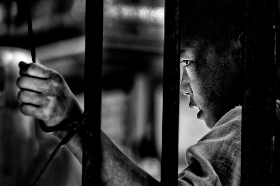 Everyday Photograph - A Young Monk Behind The Bars Of A Buddhist School by Giovanni Cavalli