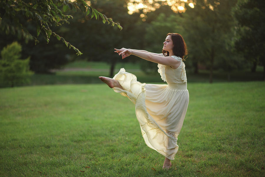 A Young Woman Dances Barefoot In A Tree-lined Park At Sunset Photograph ...
