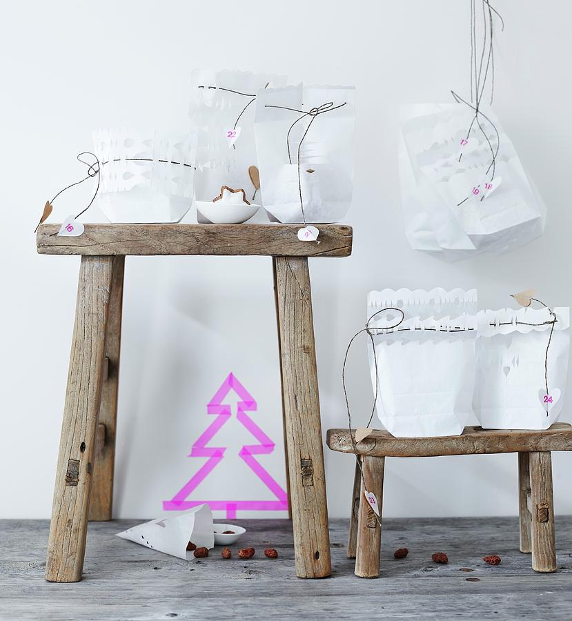 Advent Calendar Made From White Paper Bags With Cut-out Trim And Cords With Love-heart Pendants Photograph by Andreas Hoernisch