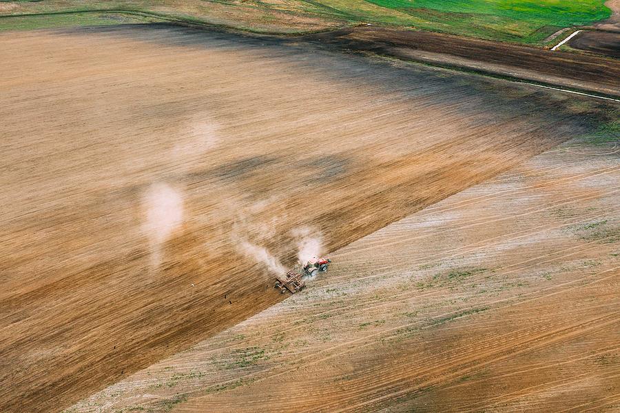 Spring Photograph - Aerial View. Tractor Plowing Field by Ryhor Bruyeu