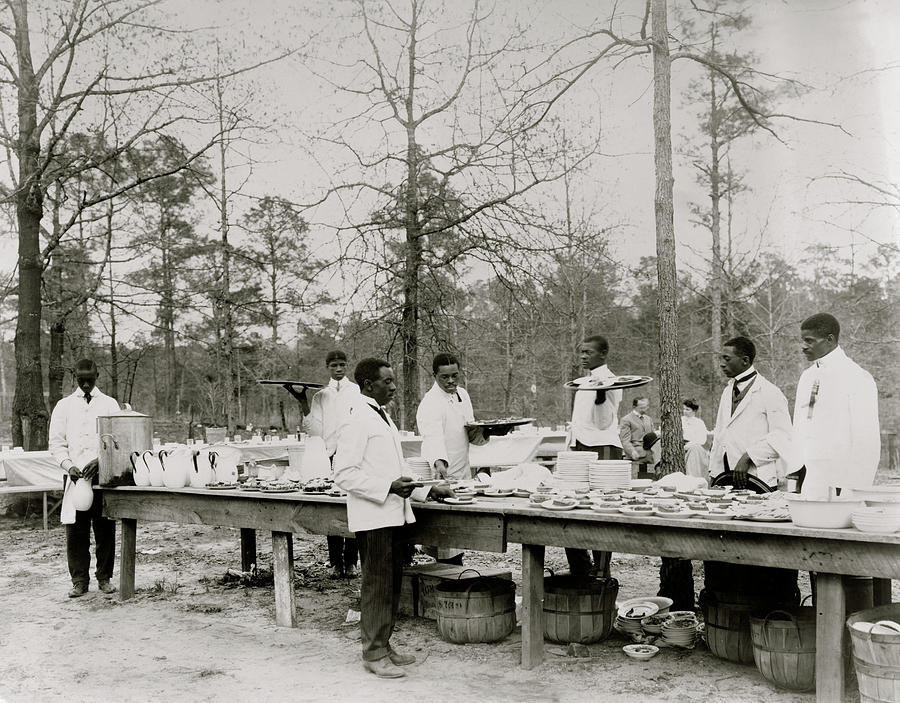 African American men preparing to serve a meal in an outdoor setting among trees Painting by Unknown