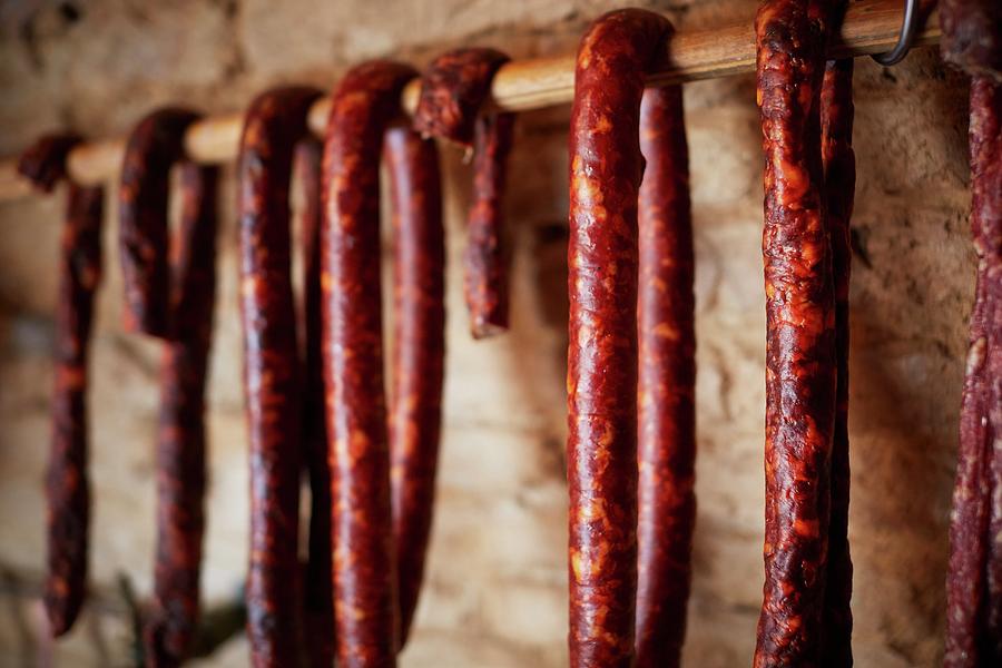 Air Dried Salsiccia Hanging From A Wooden Bar Photograph by Riccardobruni