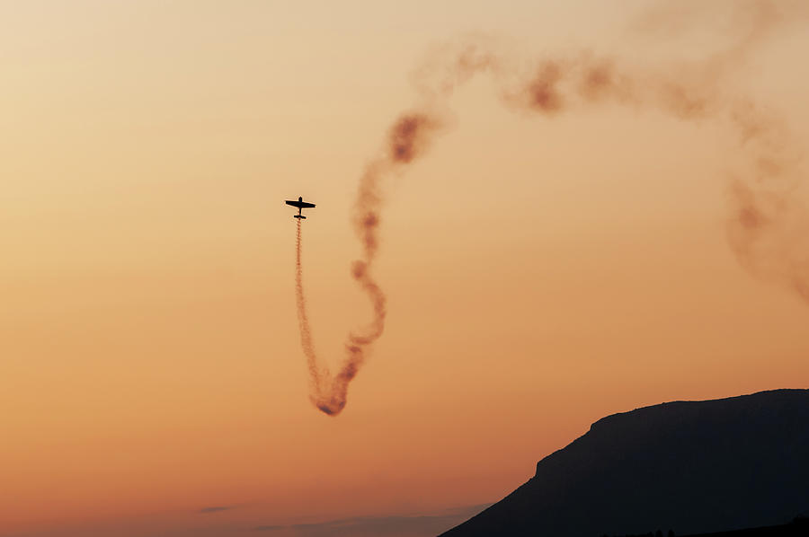 Airplane performing aerobatics on the air during sunset  Photograph by Michalakis Ppalis