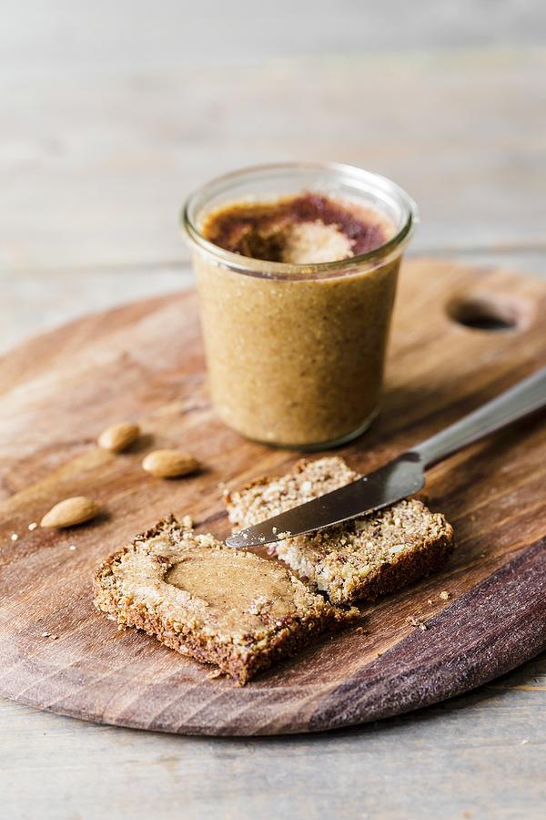 Almond And Cinnamon Butter On A Slice Of Rye Bread With A Knife And A Glass Jar Of Almond And Cinnamon Butter In The Background Photograph by Sarah Coghill