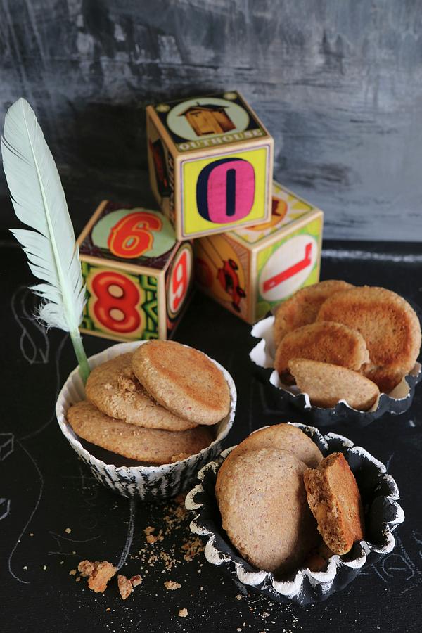 Almond Flour And Honey Biscuits In Homemade Earthenware Cases With Building Blocks And A Feather On A Black Surface Photograph by Regina Hippel