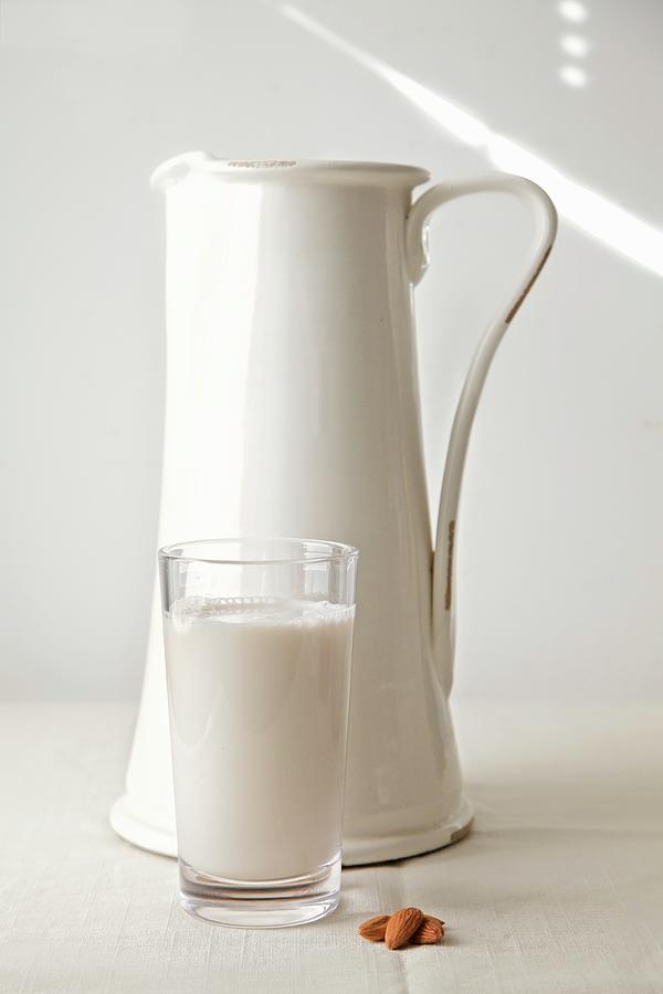 Almond Milk In A Glass In Front Of A White Jug Photograph by Andre Baranowski