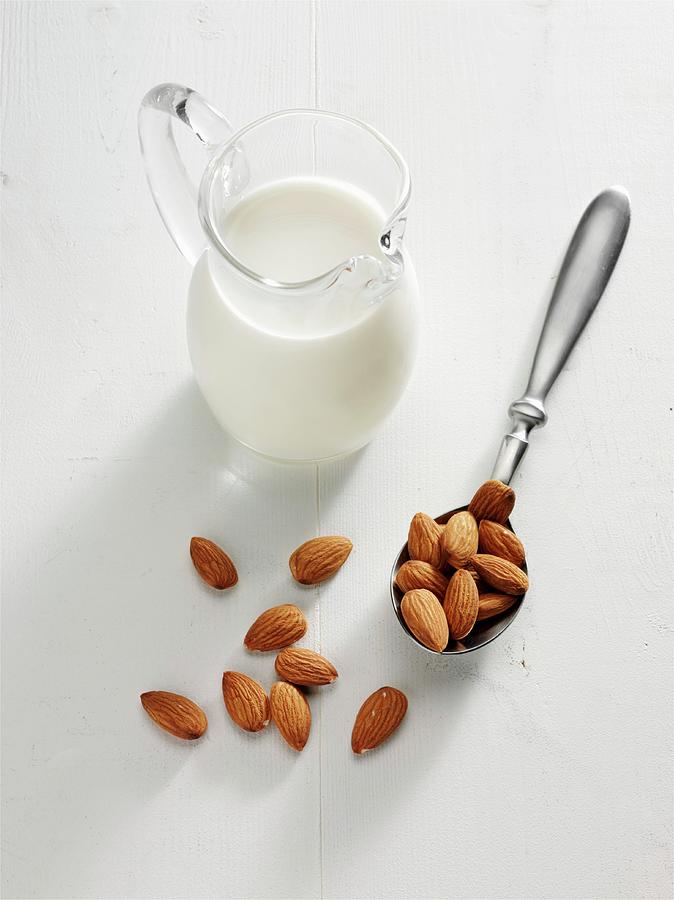 Almond Milk In A Glass Jug Next To A Spoon Of Almonds Photograph by Albert P Macdonald